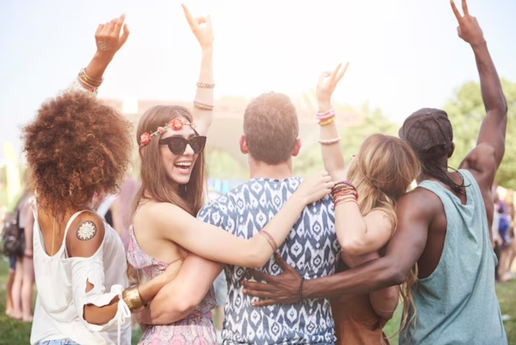 festival-goers dance together, with a woman in sunglasses and floral headband laughing brightly