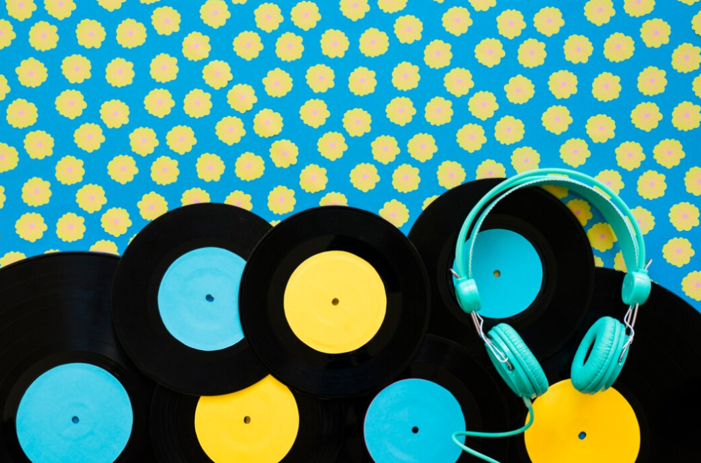 Vinyl records with blue and yellow centers and teal headphones on a floral blue fond